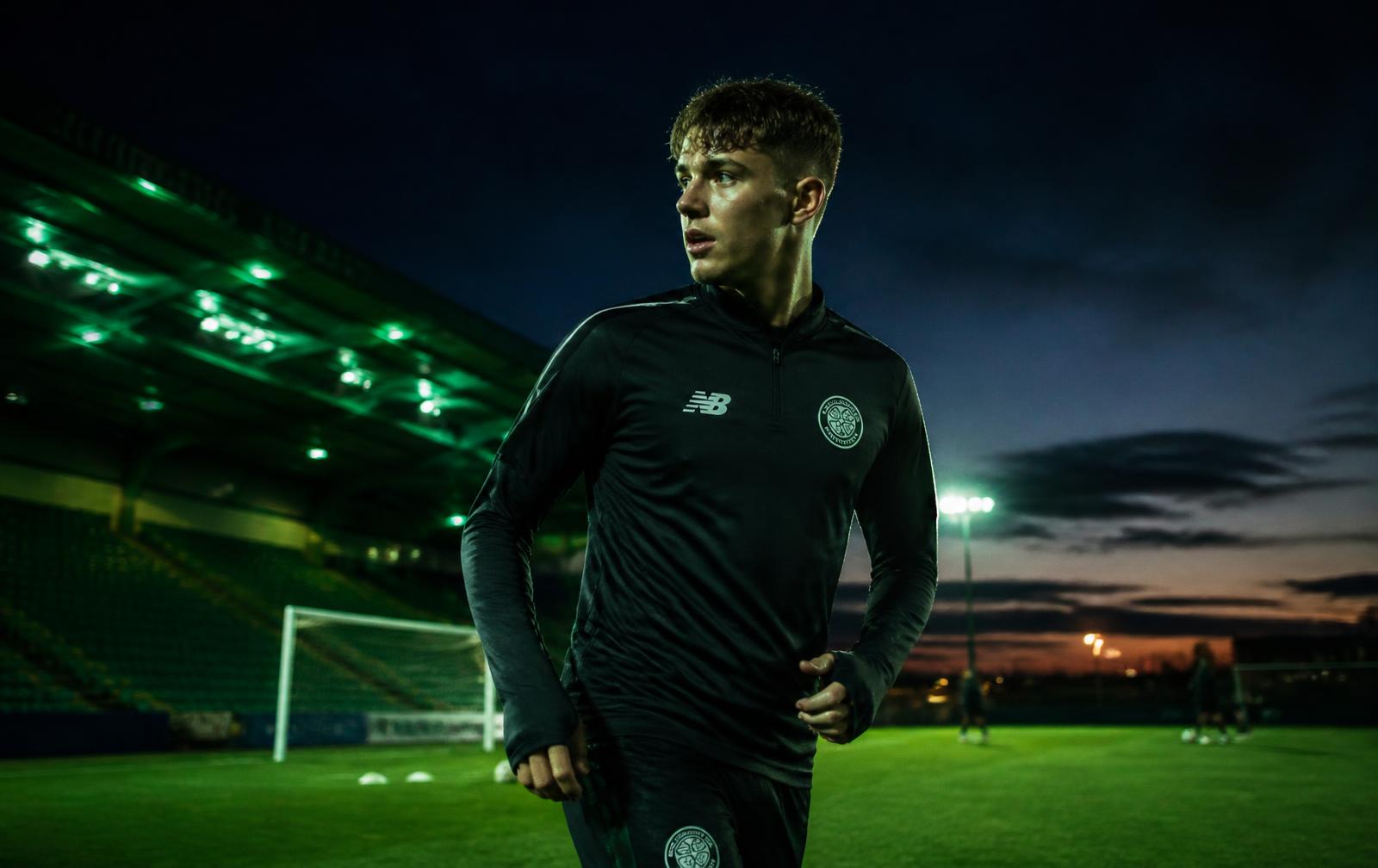 Futbolista entrenando en un estadio iluminado al atardecer